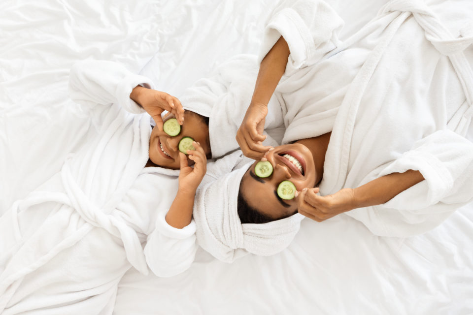 Mom And Daughter In Bathrobes Lying With Cucumber Slices On Eyes at the spa