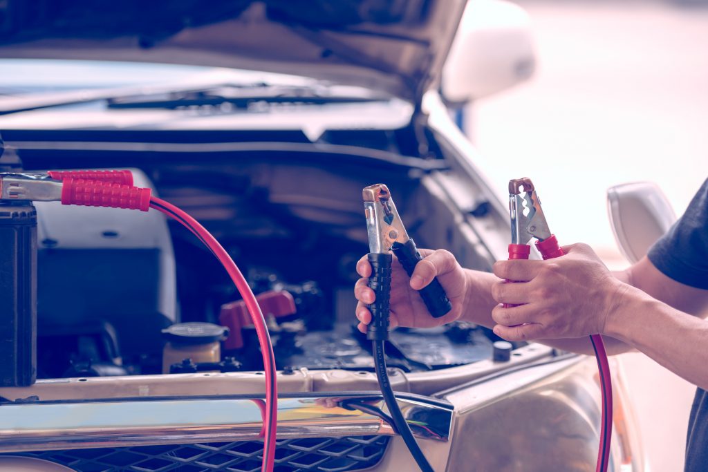 Automotive mechanic uses battery jumper cables for chargers and jump starters a dead battery, maintenance car battery concept.