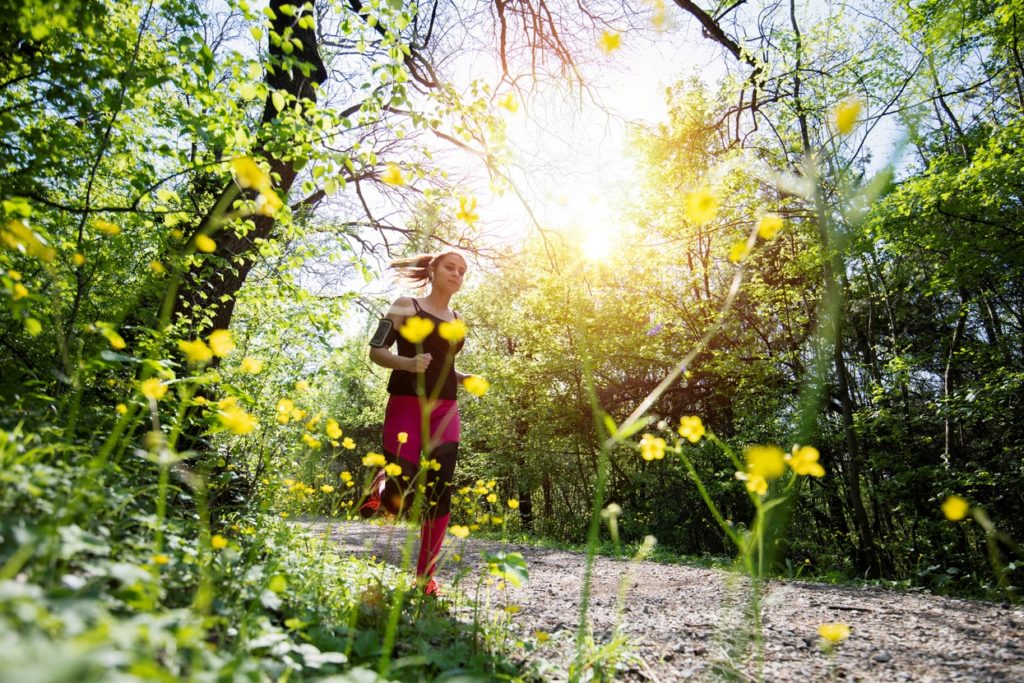 woman running along sunny green trail