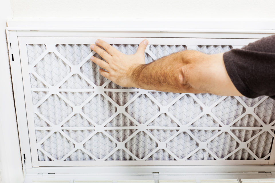 Man replacing A/C filter for a home air conditioning system.