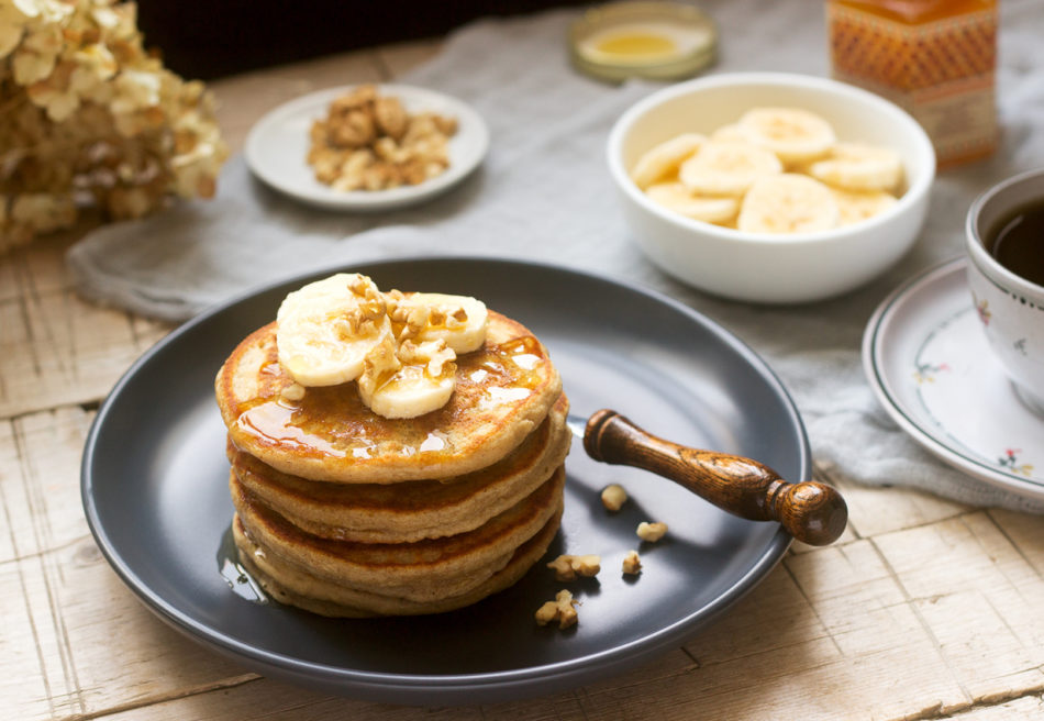 Pancakes with banana, nuts and honey, served with tea. Rustic style.