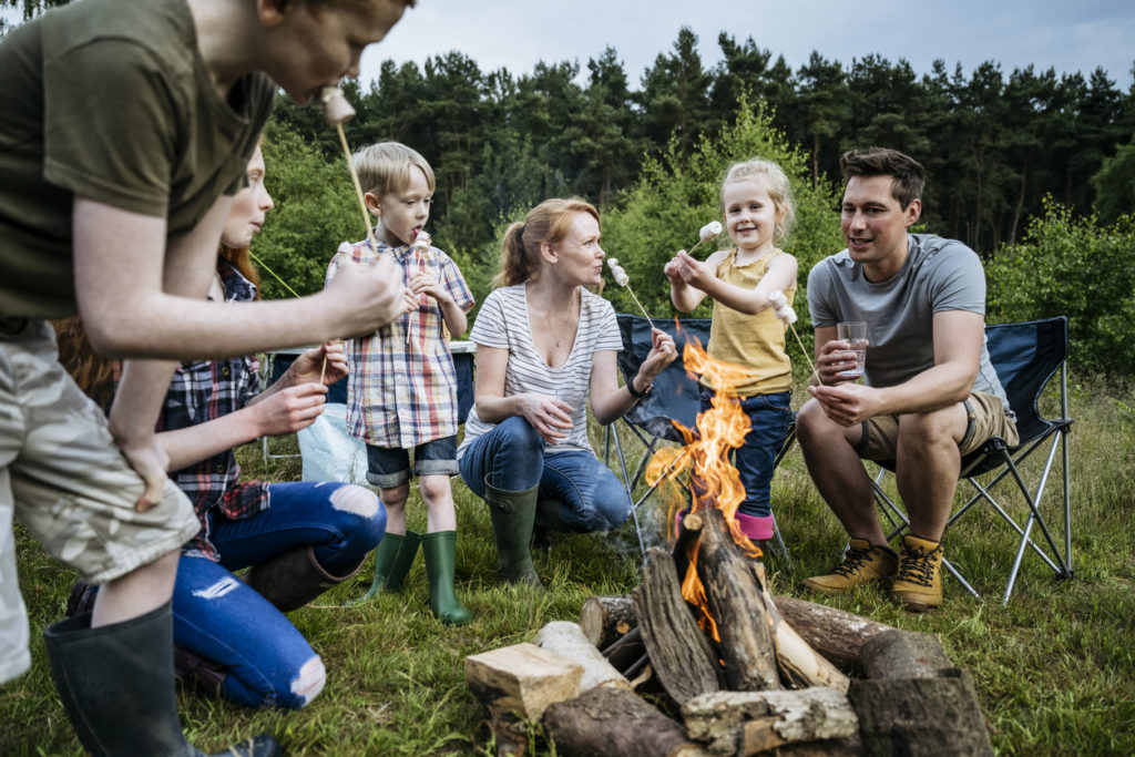 Family with four children roasting marshmallows outdoors