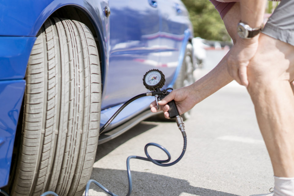 person pump up the car wheels tires with a compressor with manometer
