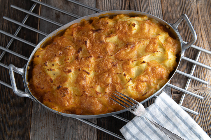 Delicious homemade fresh cooked potato gratin with mashed potato, cheese crust and delicious ground beef, vegetable filling. Served in a rustic casserole dish on wooden table from above
